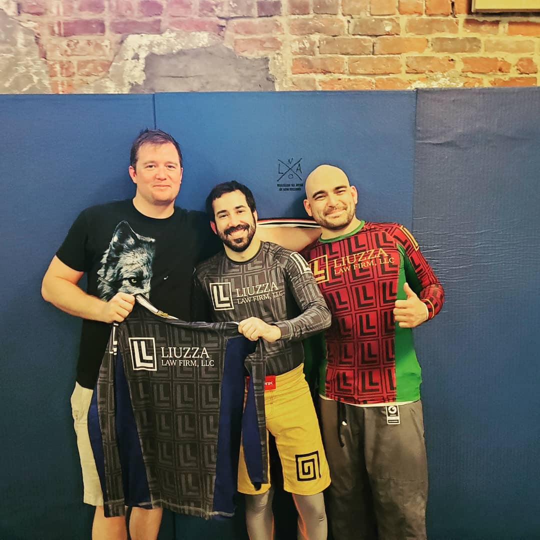 Chris Liuzza the founder of Liuzza Law Firm holding his branded rash guard in his dojo because Chris also teaches brazilian jiu jitsu